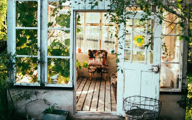 Exquisite greenhouse surrounded by sunflowers with colorful folding chair inside