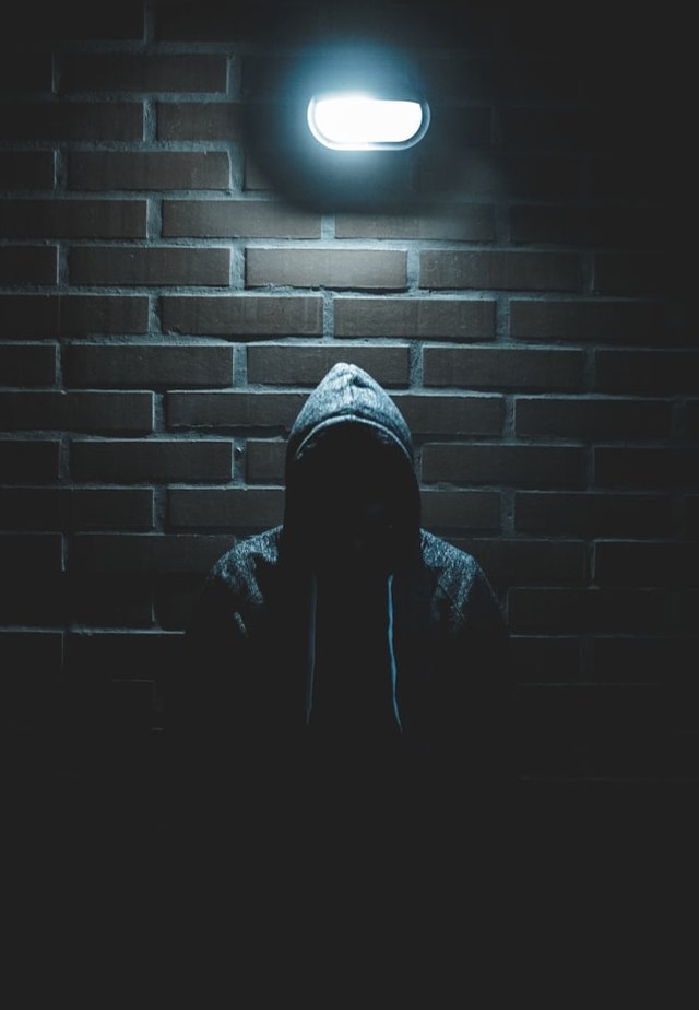 unknown person wearing a hoodie and standing under a lamp