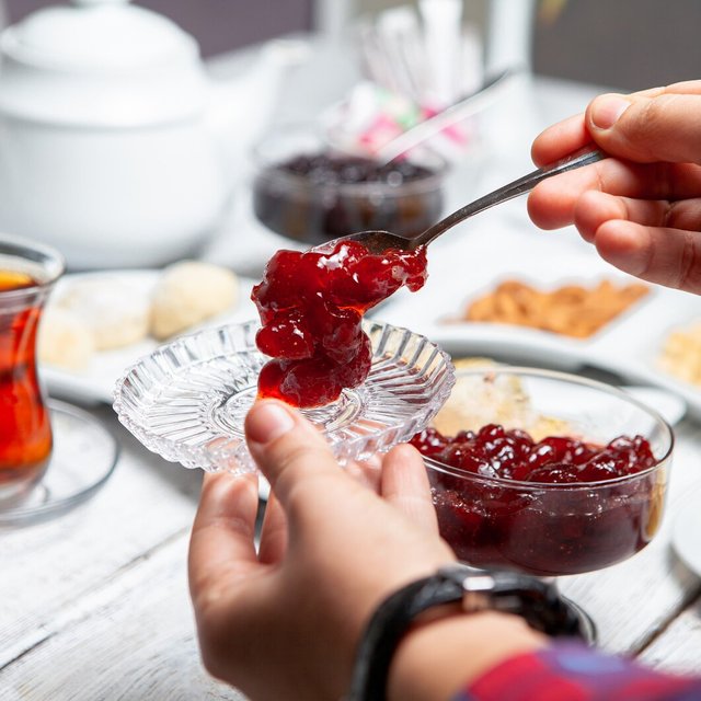 high-angle-view-man-serving-delicious-fruit-jam-with-tea-nuts-white-wooden-background_176474-3797.jpg