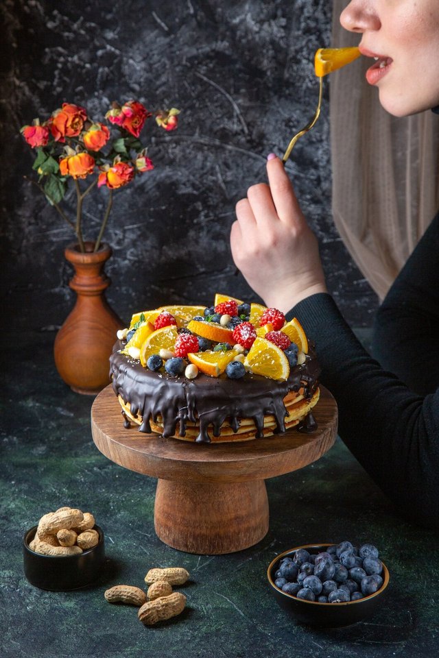 front-view-yummy-chocolate-cake-with-fresh-fruits-getting-eat-by-female-dark-wall_179666-30727.jpg