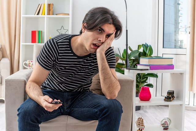 young-man-casual-clothes-holding-tv-remote-looking-tired-bored-sitting-chair-light-living-room_141793-102139.jpg
