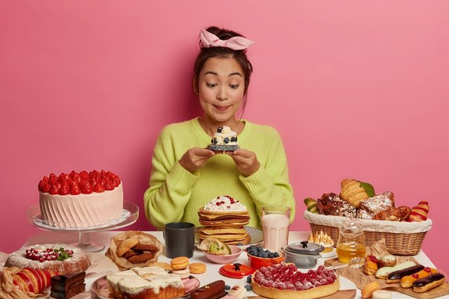 calories-food-temptation-loosing-weight-concept-korean-girl-with-lovely-appearance-looks-sweet-muffin-with-great-appetite-enjoys-delicious-treat-poses-against-pink-background_273609-34507.jpg