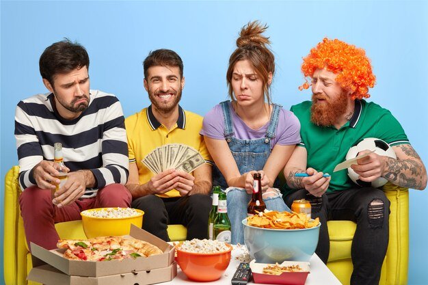 Free photo company of friends watch soccer on tv, one guy makes bet for winning his favourite team