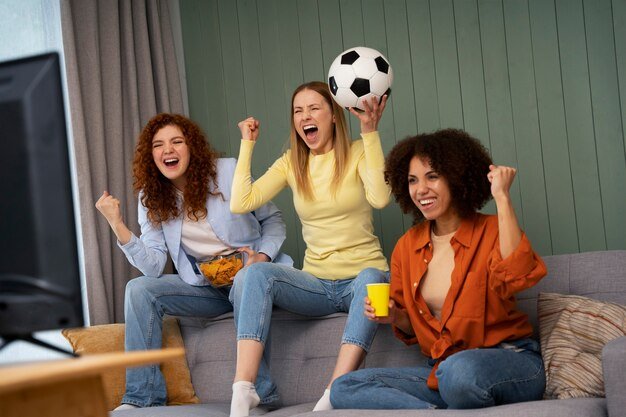 Free photo group of female friends at home watching sports together