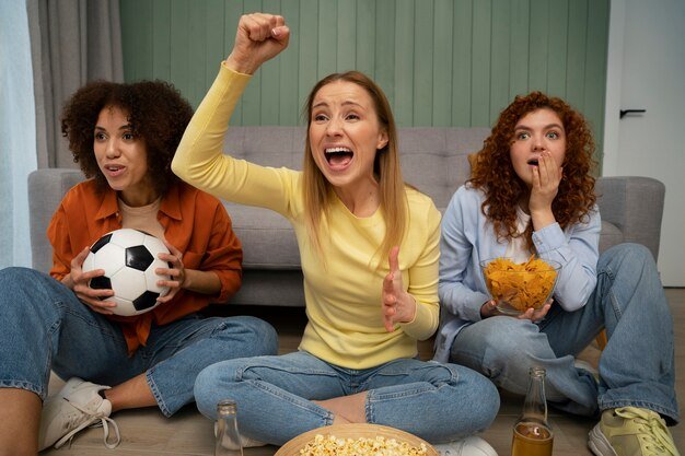Free photo group of female friends and sports fans watching tv at home together