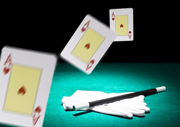 Free photo moving three playing cards in air over the pair of white gloves and wand on green backdrop