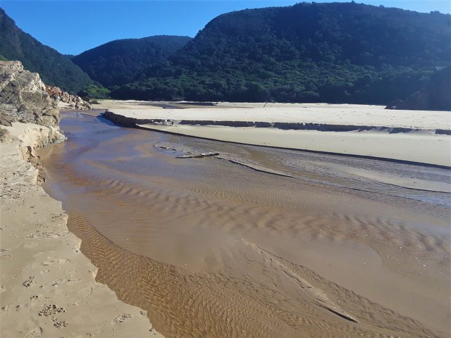 Fresh water stream flowing out to sea at the beach, looking up stream