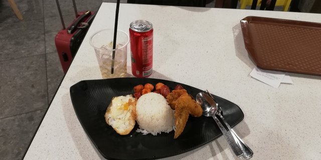 Fried wings with sunny sideup egg and chopped sausages with rice and Coke in can.