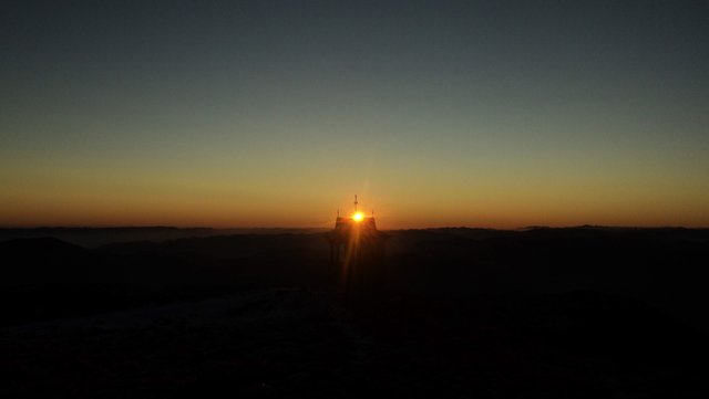 The first rays of the sun above the chapel at the top of the mountain