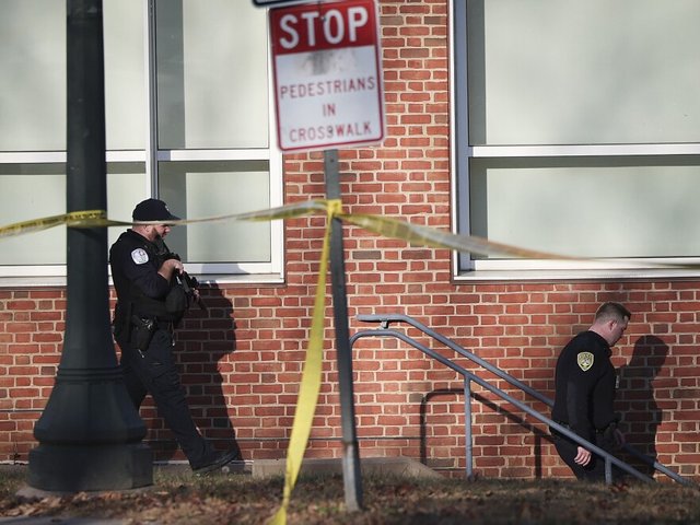 Law enforcement personnel move through the crime scene.