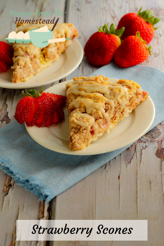 strawberry scone on white plate with cut up strawberries next to it. 