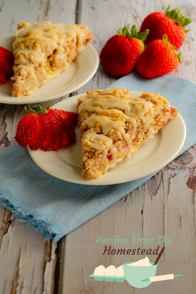 strawberry scone on white plate with cut up strawberries next to it.