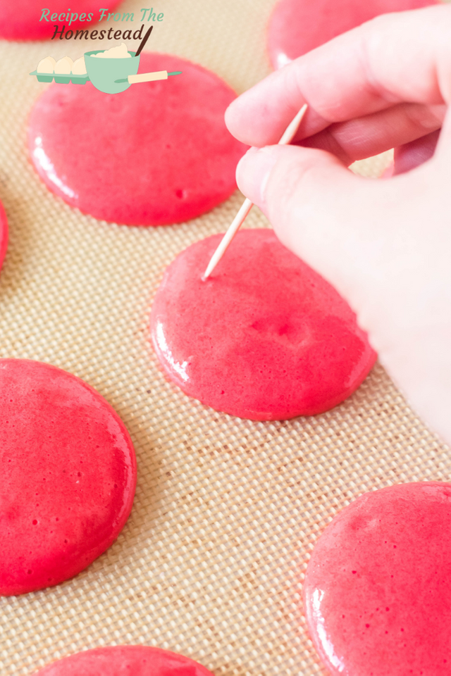 piercing macaron dough with toothpick