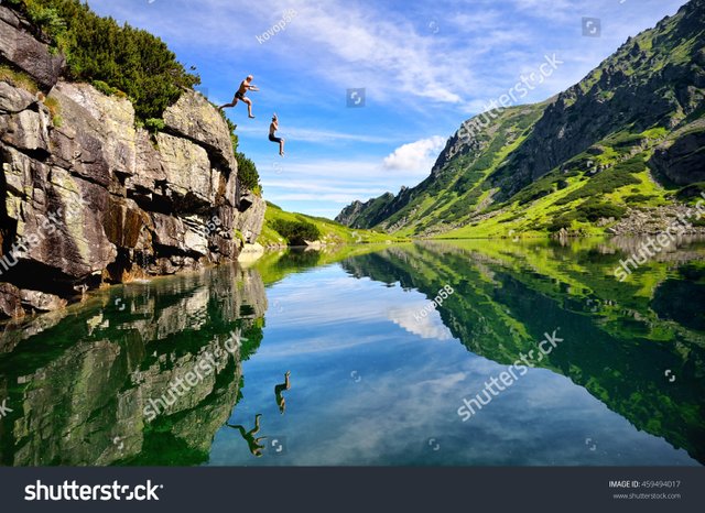 Young couple jump together into lake in mountains-with-beautiful-blue-water-and-reflexion.jpg