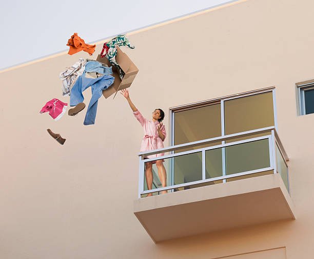 mixed-race-woman-throwing-clothes-off-balcony-picture-id187138357.jpg