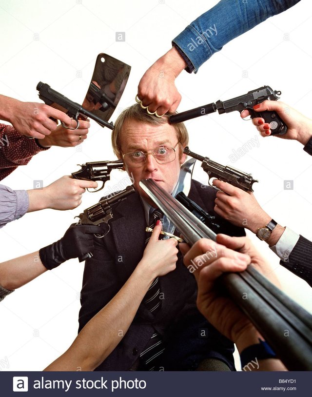 a-frightened-man-with-several-guns-pointing-at-his-head-B84YD1.jpg