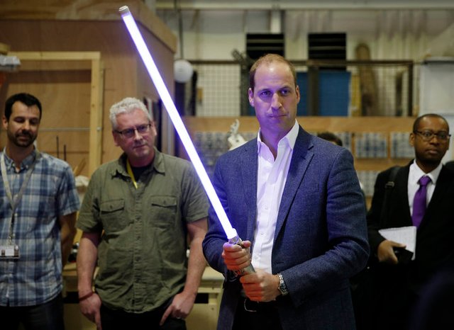 Prince William holds a lightsaber during a visit to the Star Wars film set at Pinewood Studios near Iver Heath, west of Londo