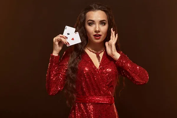 Young beautiful lucky brunette in a red evening dress shows her cards, a pair of aces — Stock Photo, Image