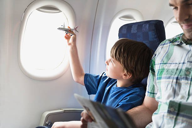 boy-playing-with-toy-plane-in-airplane-picture-id170409572.jpg