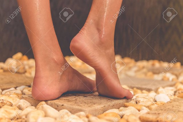 63888490-beautiful-feet-of-young-woman-standing-on-stones-while-taking-shower-in-bathroom.jpg