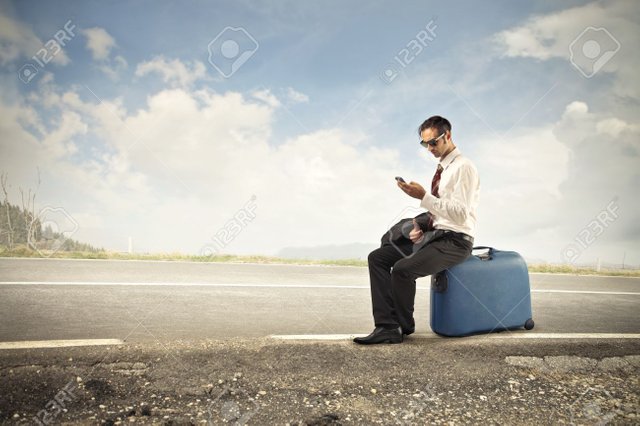 21803187-businessman-waiting-for-someone-sitting-on-his-suitcase-Stock-Photo.jpg