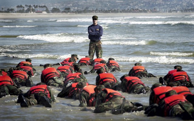 US_Navy_030415-N-3953L-039_During_a_Hell_Week_surf_drill_evolution,_a_Navy_SEAL_instructor_assists_students_from_Basic_Underwater_Demolition-SEAL_(BUD-S)_class_245_with_learning_the_importance_of_listening.jpg
