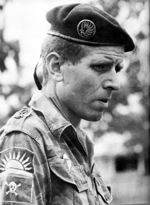 Rolf Steiner with the national flag  Rising sun  of Biafra and under it his commando´s patch, which was also worn by his men.jpg