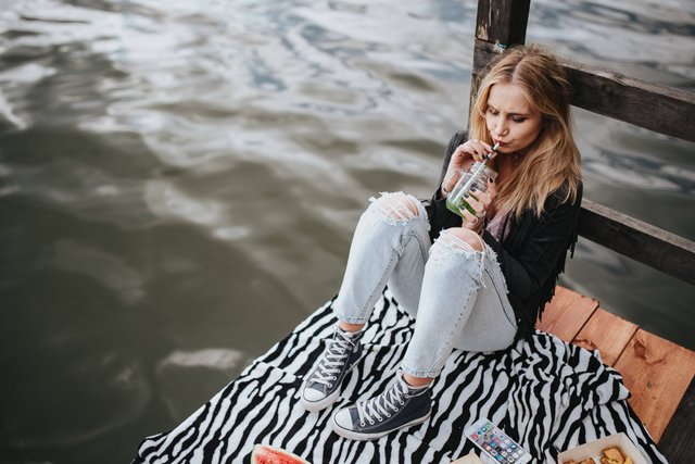 kaboompics_Blonde woman having a healthy snack at the wooden pier.jpg