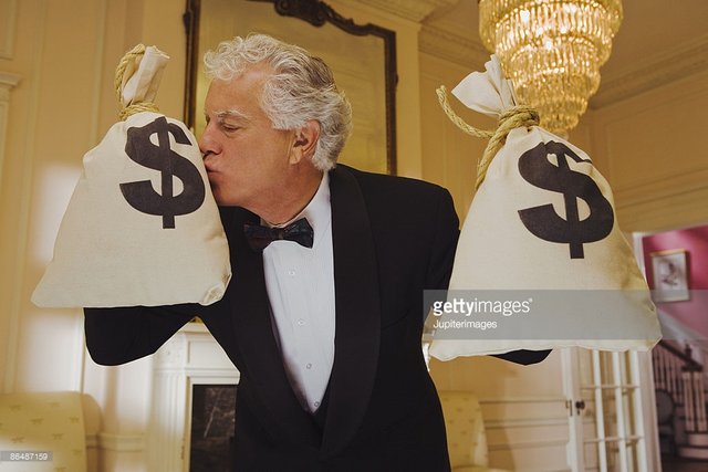 wealthy-man-kissing-money-bags-picture-id86487159.jpeg