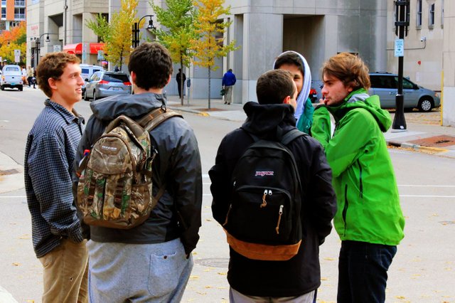 Some college students standing around on a street corner.jpg