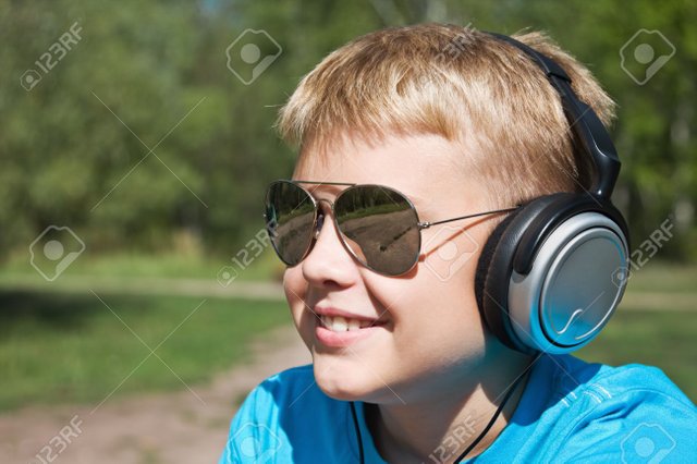 13212955-boy-listening-to-music-through-headphones-on-the-nature-Stock-Photo.jpg