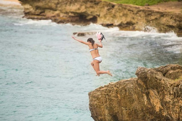 Attractive-female-jumping-off-cliff-in-Hawaii-with-snorkeling-gear-pfoc.jpg
