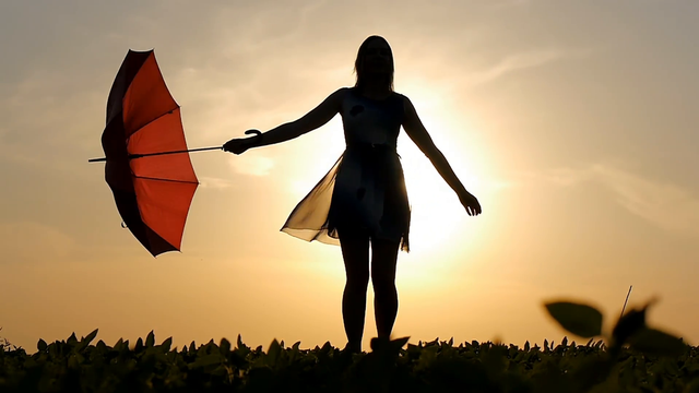 portrait-of-a-beautiful-girl-with-a-red-umbrella-in-the-sunset-smiling-emotions-green-grass-field-smiling-girl-dancing-laughing-spinning.png