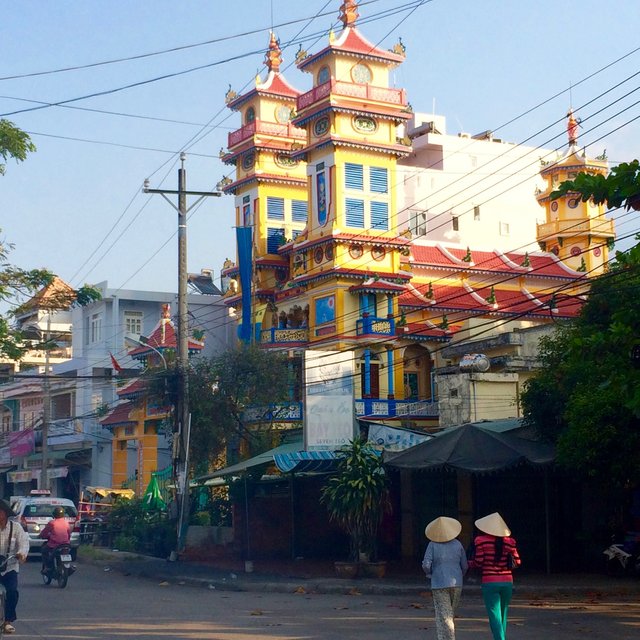 6 Two ladies wearing traditional Vietnamese Non La hats walk past the temple .jpg