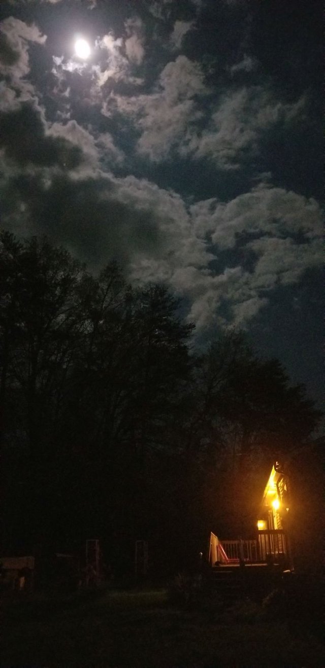 20180427_224704 - Moonlight through clouds over woods and lighted back porch.jpg