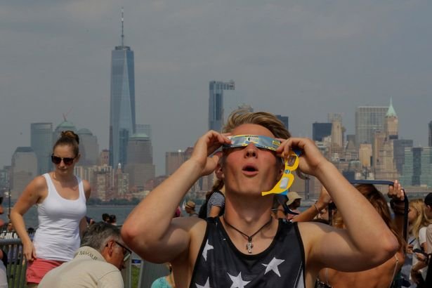 A-man-takes-a-look-at-the-solar-eclipse-at-Liberty-State-Island-as-the-Lower-Manhattan-and-One-World.jpg