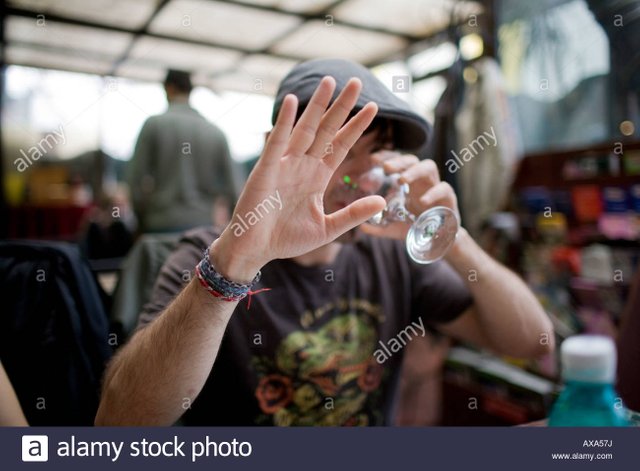 man-with-a-cap-in-a-bar-drinking-and-hiding-his-face-from-the-camera-AXA57J.jpg
