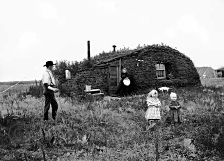 Norwegian settlers in 1898 North Dakota in front of their homestead, a sod hut.jpg