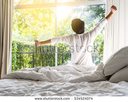 stock-photo-lazy-man-happy-waking-up-in-the-bed-rising-hands-to-window-in-the-morning-with-fresh-feeling-relax-534524074.jpg