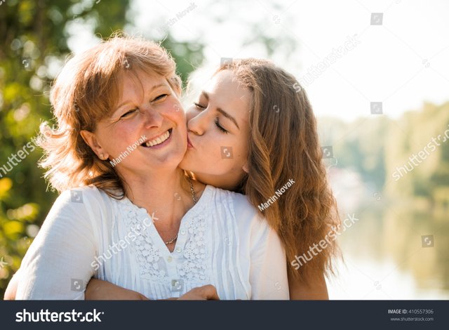 stock-photo-teenage-girl-hugging-and-kissing-her-mother-h-outdoor-in-nature-on-sunny-day-410557306.jpg