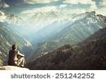 stock-photo-image-of-a-young-businessman-who-sits-on-the-top-of-the-mountain-and-looks-into-the-distance-to-the-251242252.jpg