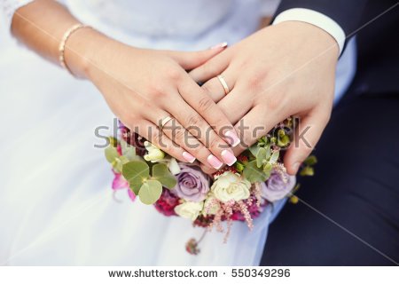 stock-photo-hands-of-bride-and-groom-with-rings-on-wedding-bouquet-marriage-concept-550349296.jpg