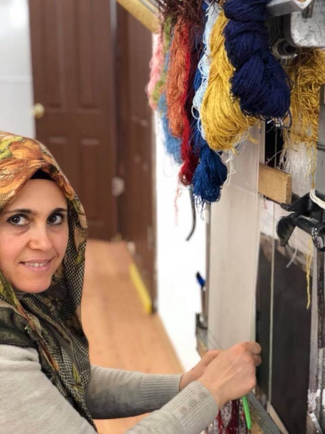 Graceful Turkish woman making a carpet at the Carpet Museum in Goreme, Cappadocia