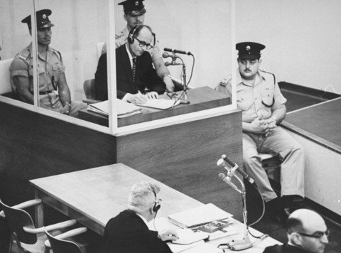 Adolf Eichmann takes notes during his trial. Photo by Israel Government Press Office. Public Domain.