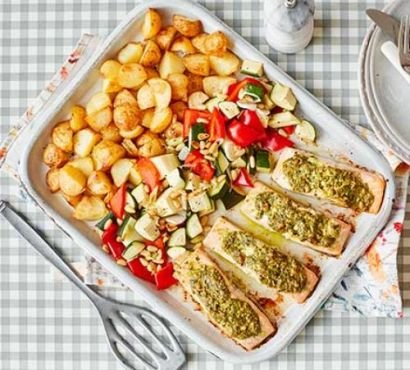 A roasting tray with salmon, vegetables and potatoes