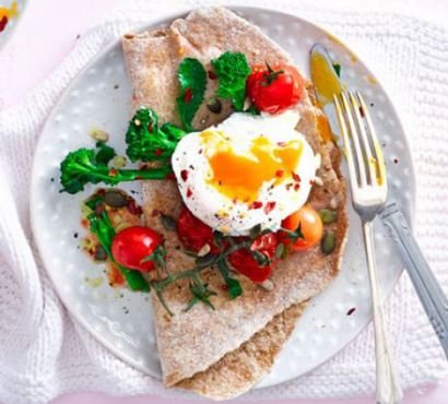 Wholemeal flatbread on a plate topped with broccoli, tomatoes and a poached egg