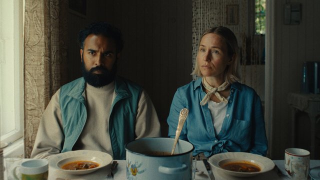 A still from the movie Bubble & Squeak, showing Himesh Patel and Sarah Goldberg cooking together in a kitchen