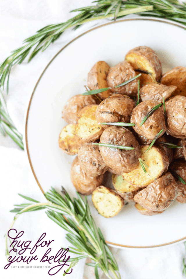 red baby potatoes on a white plate with rosemary sprigs around it