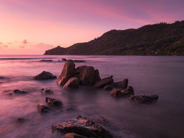 The coast of Mahe with its typical granite rocks during a colorful sunrise