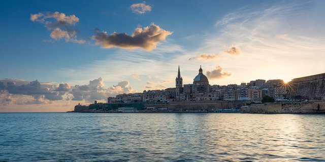 The sun peeks over the roofs of Valletta